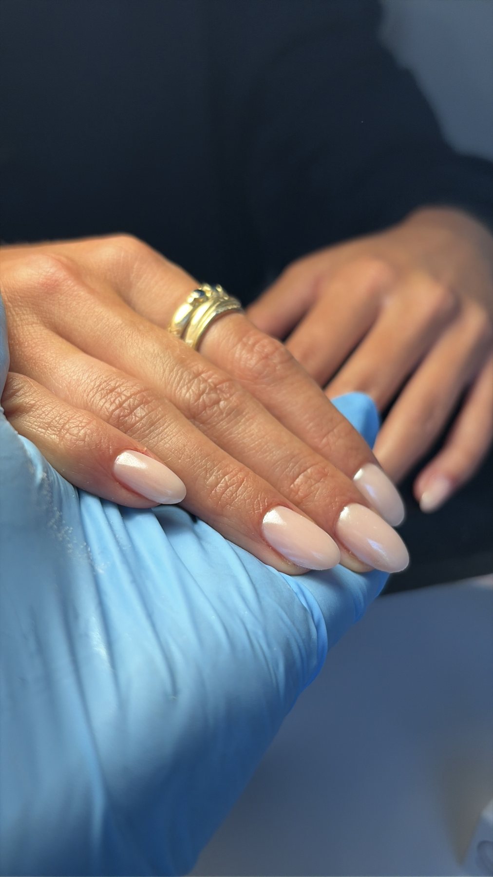Nude gelakte nagels, de hand rust op een blauwe handschoen